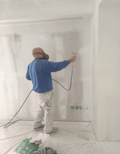 Travaux de peinture - peintre en train de peindre au pistolet à peinture