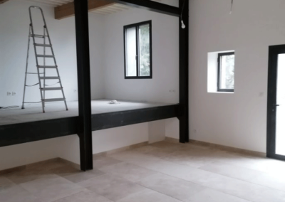 Pièce de salon, murs peints en blanc avec poutres apparentes et fenêtres