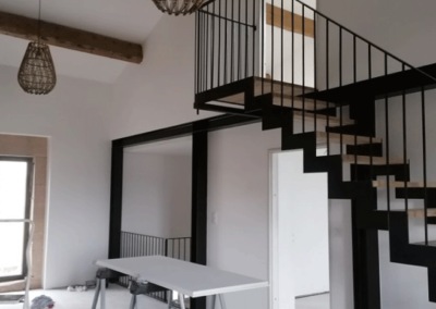 Montée d'escaliers, poutres apparentes, murs peints en blanc